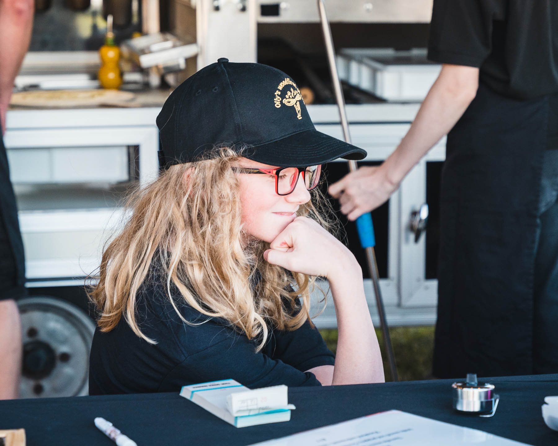 A young girl enjoying pizza from Olly's woodfired pizza mobile pizza trailer