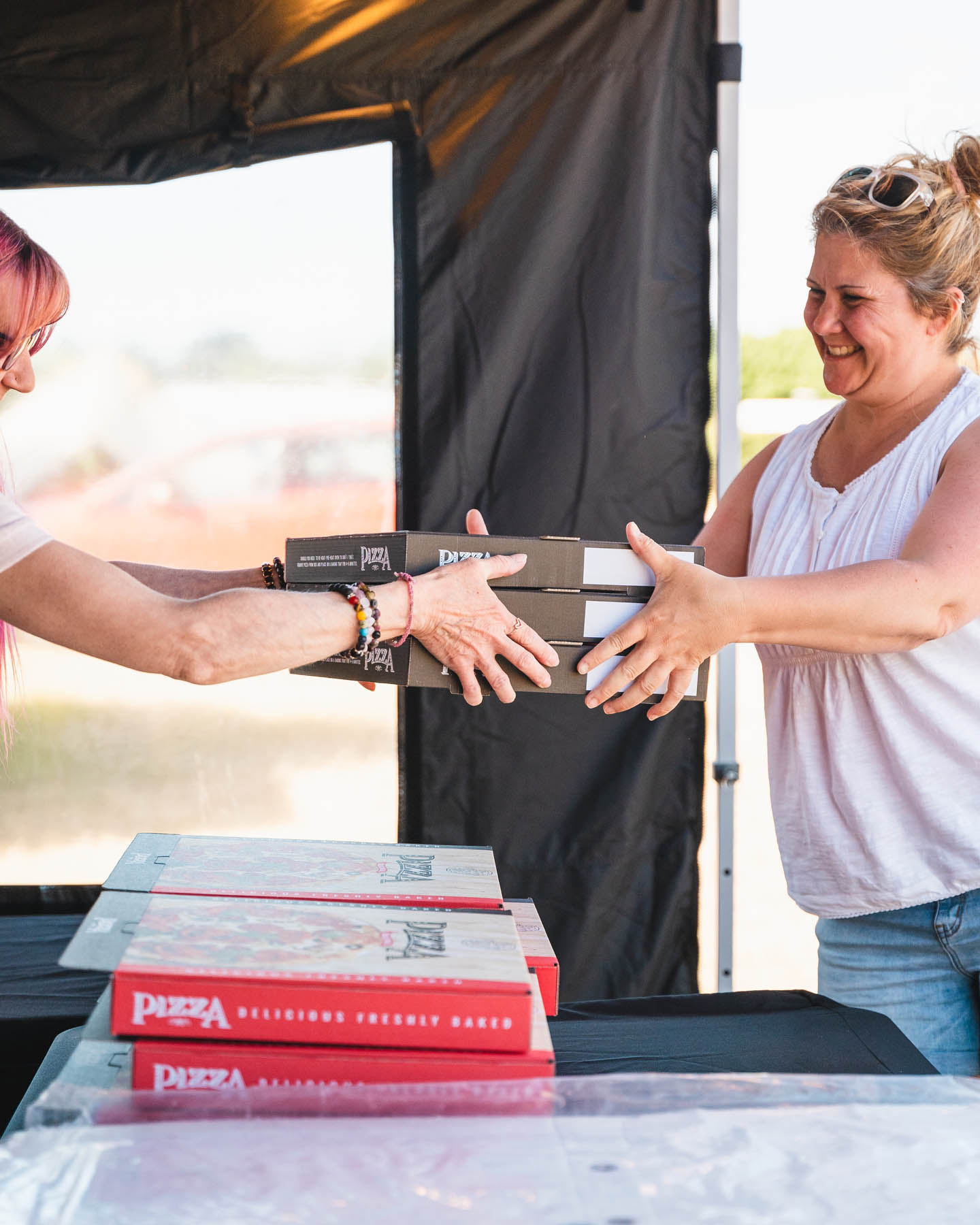 Woman collecting her order from Olly's woodfired pizza trailer in Ferndown, Dorset.